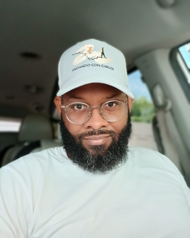 Carlos, founder of Andando con Carlos, wearing the brand cap inside his vehicle