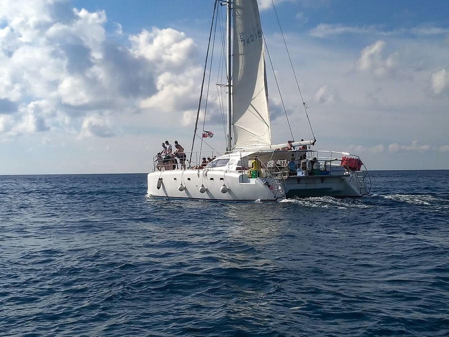 A catamaran with visitors sailing on deep blue Dominican waters