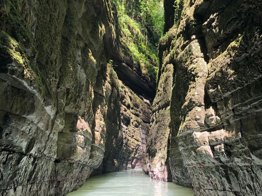A narrow canyon with clear water between tall rock walls