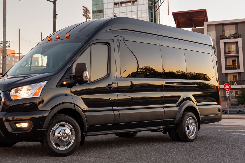 A black passenger minivan parked on a city street at sunset