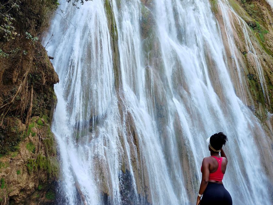 A woman standing at the foot of the El Limón waterfall in Samaná